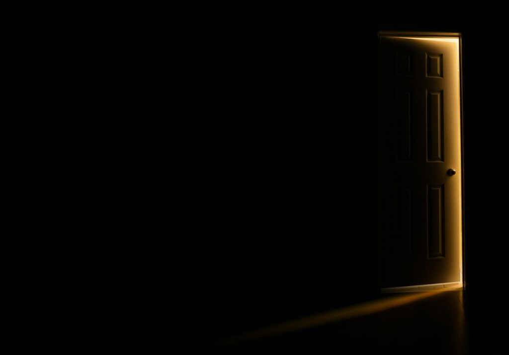 an open door in a dark room with light coming in